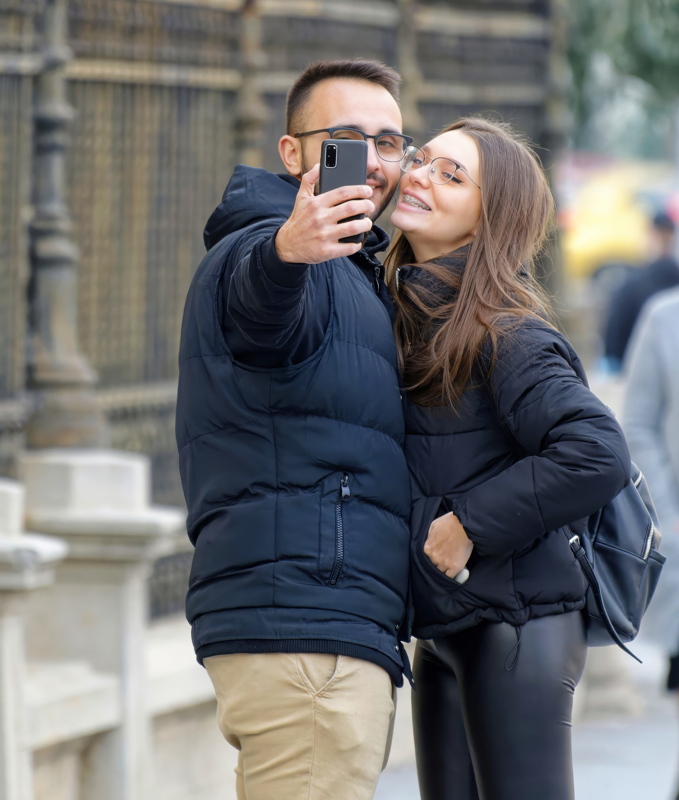 16 - A couple taking a selfie outdoors while wearing casual winter outerwear